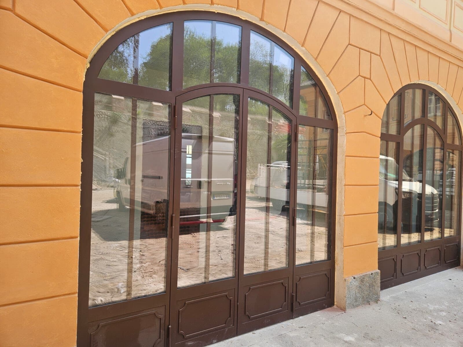 Due arcate di un portico storico chiuse da portali vetrati in alluminio color bronzo